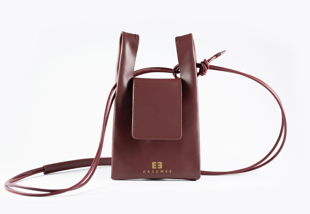 Burgundy leather crossbody bag with a strap on a white background