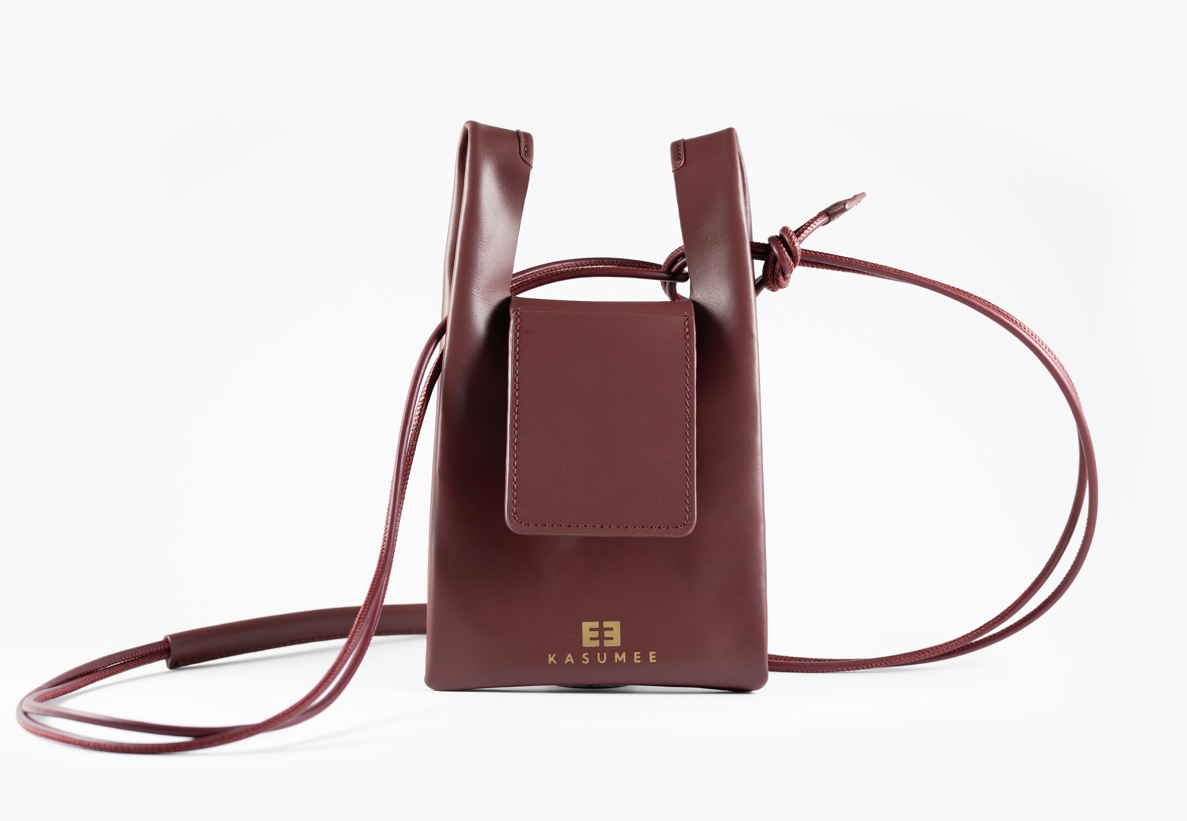 Burgundy leather crossbody bag with a strap on a white background