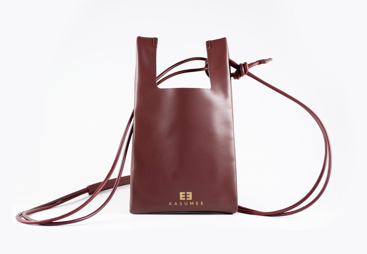 Burgundy large leather crossbody phone bag by KASUMEE, front view with gold logo and long thin leather strap