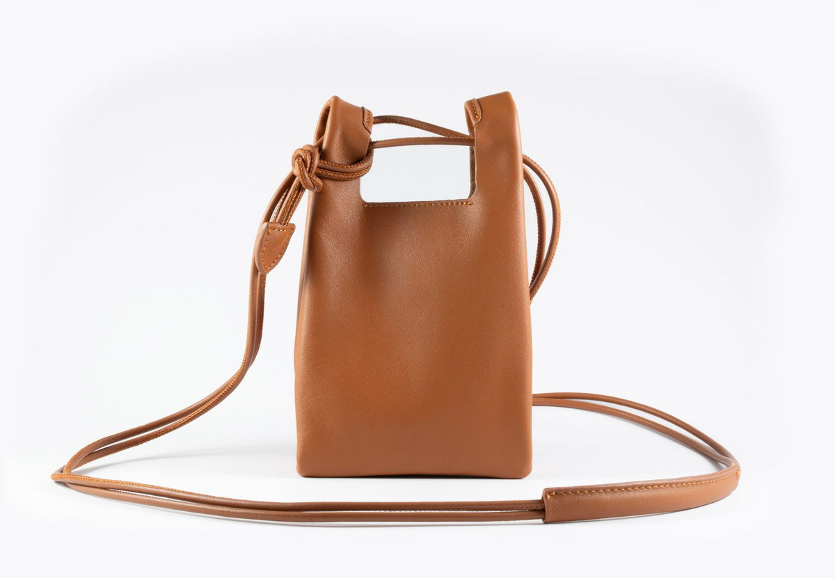 Back view of the KASUMEE caramel leather phone bag showing the knotted strap and open top